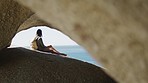 Beach, cave and woman on an adventure on vacation to relax in nature by the seaside in Hawaii. Travel, freedom and girl with a backpack relaxing on rock to explore by ocean on fun holiday or journey.