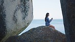 Photograph, beach and peace with a woman in nature, sitting on a rock boulder to enjoy the ocean view of the horizon. Water, travel and freedom with a female by the sea to relax on summer vacation