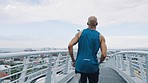 City bridge, running and black man athlete doing fitness, training and sport energy exercise. Runner, exercise and wellness workout of a man with motivation outdoor doing cardio for health and body