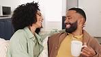 Black couple, smile and relax on sofa together in living room of modern New York apartment while drinking coffee. Happy people, black man and black woman relax, hug and laugh on couch in winter home 