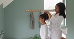 Mother, girl kid and hair care in bathroom, family home and morning routine together. Happy young child hug mom while grooming curly hairstyle, ponytail and bonding with free time, lifestyle and love