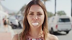 Face, portrait and woman blowing bubblegum in city, street or outdoors. Freedom, comic or funny, carefree and happy female eating gum, laughing and smiling downtown, having fun or being playful alone