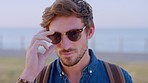 Face, man and sunglasses for beach travel, tourism and summer vacation, holiday and happiness in Sweden. Portrait, trendy shades and cool, handsome and young guy, gentleman and dude smile in sunshine