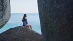 Woman, beach or relax for peace, view or summer holiday. Female, girl or tourist enjoy ocean, seaside vacation and calm for meditation, focus and thinking for travelling, yoga and zen on rock boulder