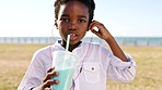 Child, earphones and drinking milkshake outside while listening to music and having fun. Earbud, drink and little african american boy kid playing outside while enjoying summer with a portrait