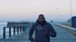 Black man, running and runner speed of exercise, training and workout at sunset by the sea. Sport run, energy and marathon cardio of athlete on beach promenade concrete for body fitness and wellness