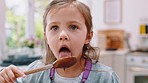 Baking, chocolate and girl lick spoon in kitchen enjoying cake, muffins and cupcake mixture. Family home, childhood and face of young child with wooden spoon to taste sweet food, dessert and batter