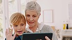 Grandmother, child and tablet in video call waving, blowing kiss or virtual greeting at home. Grandma sitting with little boy holding touchscreen in online call with smile together for communication