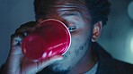 Black man, night and drinking alcohol in red party cup while talking, social and having fun at a celebration for new years or birthday. Happy male having conversation while having drinks in dark room