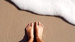 Top view, beach and person feet in waves, wave and beach sand for wellness, freedom and summer vacation, holiday and zen. Closeup feet, legs and water splash from sea, calm ocean and tropical travel 