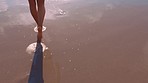 Feet, walking and water with a woman legs in the sand by the sea or ocean during summer vacation or holiday. Beach, nature and freedom with a female taking a walk alone in the current, tide or waves