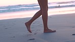 Feet, sand and woman walking along a beach at sunset, relax and calm, peace and travel in nature. Legs, girl and walk at the ocean at sunrise, adventure and explore on summer holiday in california  