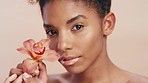 Skincare, beauty and black woman with flower on studio background, model with smile on face. Nature, luxury and natural skin care product ingredients for facial or makeup on happy woman with orchid.