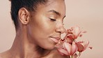 Black woman, face or skin glow with flowers on pink studio background in organic dermatology, vegan cosmetics or self love. Zoom, beauty model or facial makeup with orchids plants in natural wellness