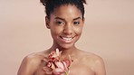 Black woman, face and flower in beauty skincare, hygiene or natural treatment against studio background. Portrait smile of African American woman model holding plant in organic care for perfect skin