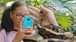 Phone, nature and girl with snake in hands enjoying trip to petting zoo, animal sanctuary and wildlife garden. Natural environment, pet and friends with smartphone for social media picture of reptile