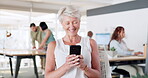 Elderly business woman, phone and smile for social media, texting or chatting for communication at office. Happy senior female CEO enjoying online conversation on mobile smartphone at the workplace