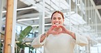 Woman in office walking with heart sign, hands and smile,  happy corporate leadership in creative startup company. Happiness, business and love hand gesture, happy woman management at design agency.