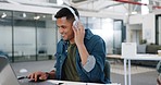 Laptop, headphones and creative man in business workspace, desk or office listening to music for productivity, metal health and inspiration. Website design worker working on pc with audio technology
