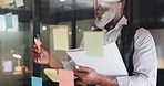 Strategy, planning and black man with sticky notes on glass wall brainstorming for new project. Development, motivation and small business startup at at night, man thinking and writing notes for idea