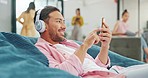 Headphones, phone and business man on sofa in office typing, social media or texting. Cellphone, bean bag relax and male worker on break streaming music, radio or smartphone podcast in busy workplace