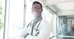 Portrait, healthcare and trust with a black man doctor standing arms crossed in a hospital hallway. Health, medical and insurance with a male medicine professional working in a clinic for treatment