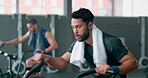 Exercise bike, fitness or towel with a man athlete sweating in a gym for cardiovascular workout. Elliptical machine, exercise and breathing with a male cycling to increase health, cardio or endurance