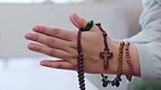 Closeup, hands and rosary for prayer, worship and spiritual practice for guidance, support and wellness. Zoom, faith beads and cross for holy religion, praying and trust with gratitude, hope and help