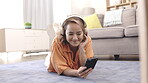 Asian woman with headphones, phone and music relax on carpet in lounge for mental health, calm and happy. Person on floor in living room listening to audio tech on cellphone, smartphone or mobile app