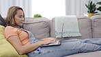 Search, laptop and relax with woman on sofa in living room for social media, website and browsing. Remote work, studying and freelancer with girl typing at home for technology, email and internet 