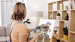 Woman painter back, home studio and design for flowers, creativity and artistic vision in living room. Girl, paint and art for focus, goals and ideas with creative flower, thinking and development