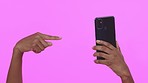 Hands point, phone and studio closeup for notification, online shopping or social media by purple background. Black woman, smartphone or gesture to check app, web and sale alert with retail discount