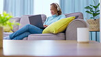 Laptop, couch and headphones of asian woman typing, online career research and listening to music for work from home. Young entrepreneur, freelancer or person working on computer, sofa and audio tech