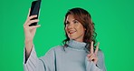 Woman, peace sign and smile for selfie, vlog or profile picture against a green studio background. Happy female making silly, goofy or funny face for photo, social media or online post on mockup