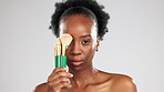 Face, makeup and black woman with brushes in studio isolated on a gray background. Portrait, facial cosmetics and young female model with product or tools to apply foundation or powder for beauty.