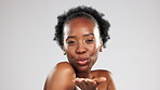 Kissing, friendly and black woman blowing a kiss as a portrait happy and excited isolated in studio grey background. Young, beauty and attractive skincare model flirt with lips or mouth gesture