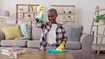 Wiping, table and portrait of a woman cleaning the living room for housework and chores. Happy, spraying and African girl with detergent, cloth and product to clean a desk with spray in the lounge