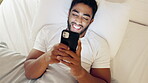 Happy man, phone and lying on bed for social media, chatting or texting while relaxing with smile at home. Relaxed male smiling on smartphone in bedroom browsing, streaming or enjoying entertainment