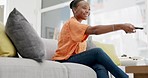 Funny, black woman on couch and relax with remote, happiness and peace in living room. African American female, lady and watching television on sofa, laughing or smile with break, comfortable or rest