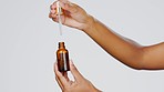 Closeup, hands and pipette for skincare, cosmetics and dermatology against a grey studio background. Zoom, hand and bottle with serum, collagen and oil for treatment, grooming and product for beauty