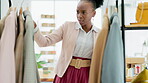 Black woman, fashion and checking clothing rack in logistics or small business in retail warehouse. Happy African American female clothing designer looking at clothes in stock for quality assurance