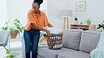 Black woman, cleaning and laundry basket with clothes and clean living room with housekeeping and tidy up. Female cleaner, domestic service and housekeeper with hygiene, neat and house work 