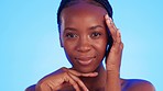 Black woman, beauty and hands on face in studio for wellness, hygiene and smooth skin on blue background. Skincare, portrait and girl model relax with luxury, glow and cosmetic result while isolated 