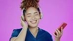 Phone, music and black woman with headphone dance in studio for relax, chilling and happy on smartphone. Fashion, dancing and girl face on purple background listen to track, streaming audio and radio