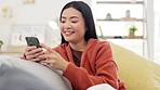 Asian woman, smartphone and laughter at funny meme on social media with communication and chat. Happy female using phone, typing and relax on sofa, comedy online and connectivity with technology