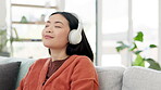 Music, audio and woman relax listening to a song in a home sitting on a couch or sofa enjoying the radio in an apartment. Joyful, happy and young person in living room having fun with headphones