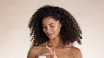 Face, skincare and lotion with a model black woman in studio on a brown background to apply treatment. Portrait, beauty and moisturizer with an attractive young femae applying an antiaging product