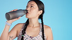 Athlete, fitness and woman drinking water bottle to refresh or rest from exercise, workout and training or sports. Asian, hydration and thirsty female rest isolated against a studio blue background