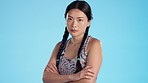 Face, angry and Asian woman with arms crossed, frustrated and girl against a blue studio background. Portrait, Japanese female and lady with stress. anger and emotional rage with hate and furious