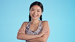 Portrait, fitness and woman arms crossed happy for exercise or workout isolated in studio blue background and excited. Asian, laughing and person ready for training for health or wellness